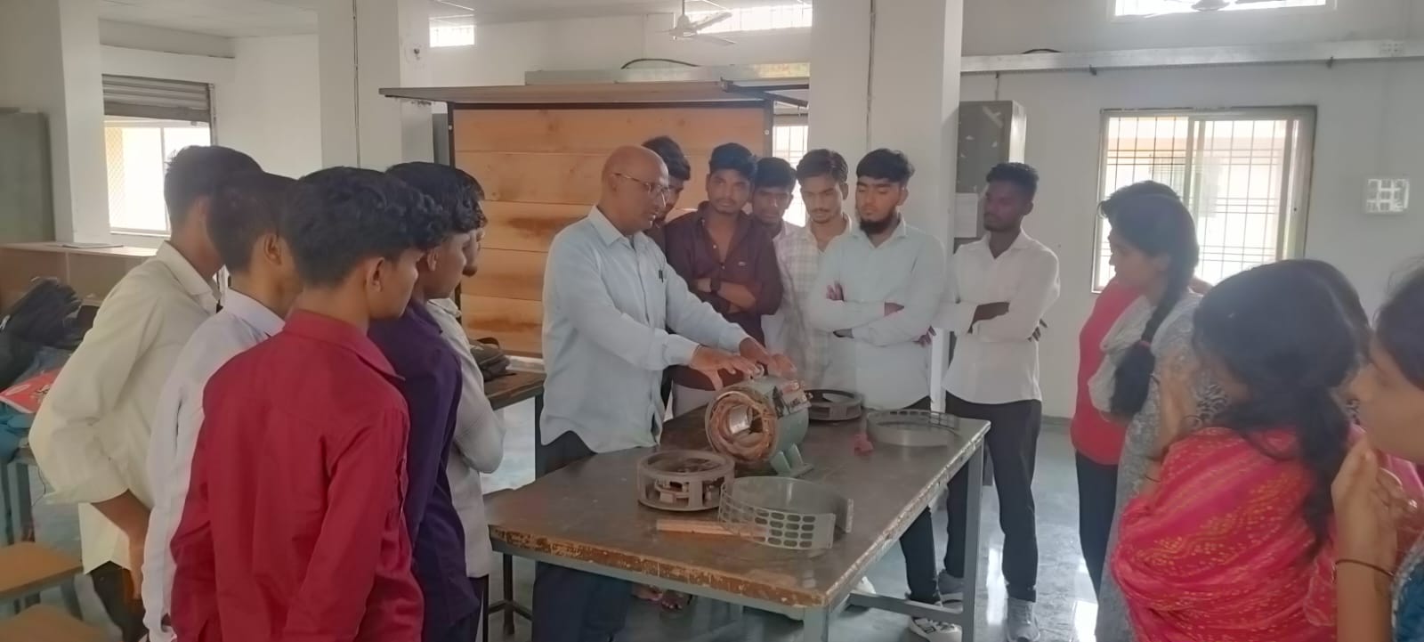 Instructor guiding electrician trainees through motor winding